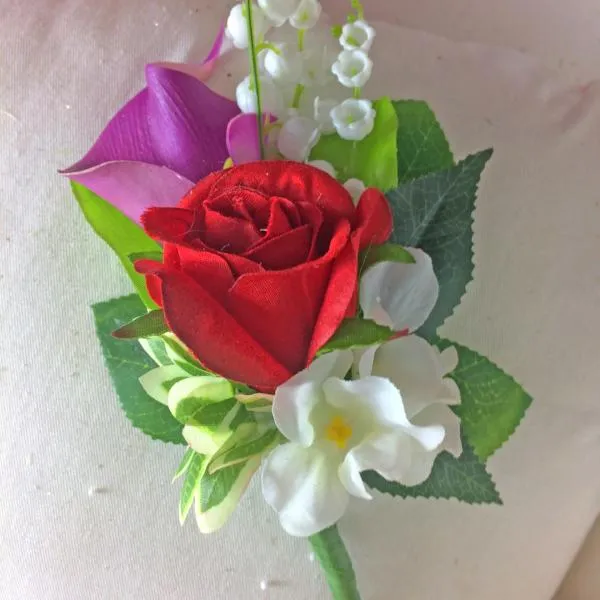 A wedding corsage of rose, calla lily and lily of the valley plus foliage